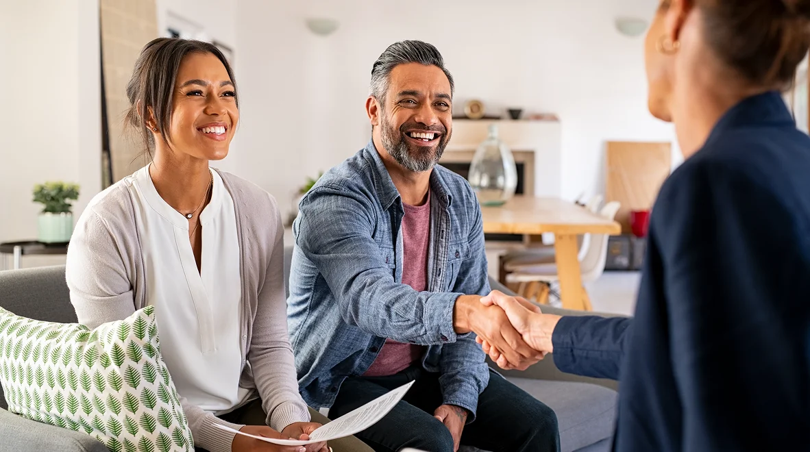 Couple meeting professional, shaking hands, smiling.