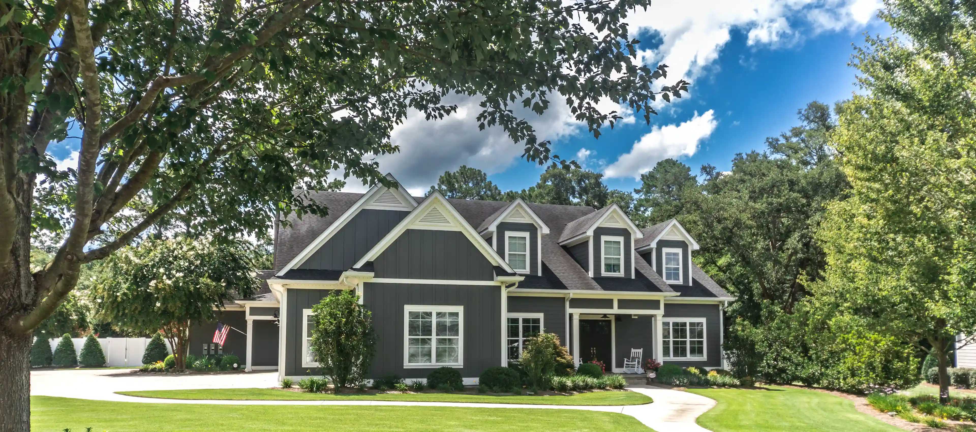 Gray house with trees and blue sky.